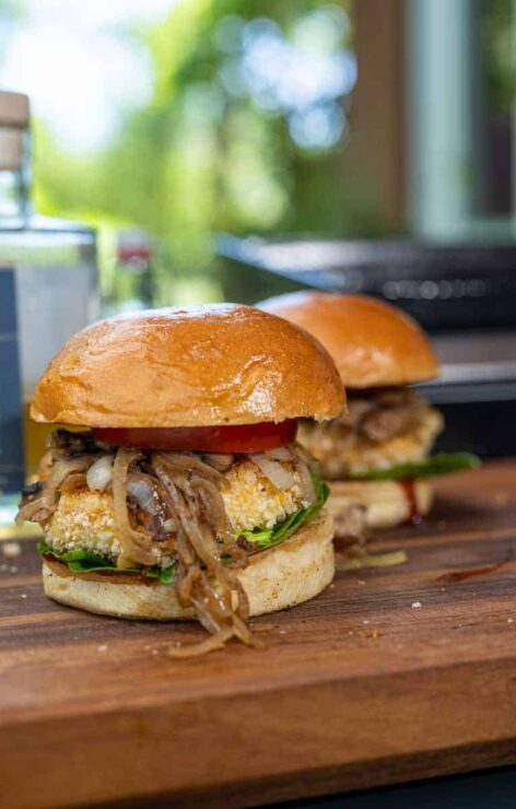 Vegetarischer Burger mit paniertem Grillkäse und Whisky-Zwiebeln Knuspriger Reggie Burger mit paniertem Grillkäse, frischen Tomaten, Salat und BBQ-Soße auf geröstetem Bun