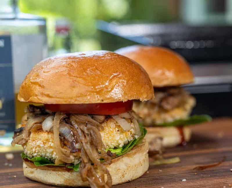 Knuspriger Reggie Burger mit paniertem Grillkäse, frischen Tomaten, Salat und BBQ-Soße auf geröstetem Bun