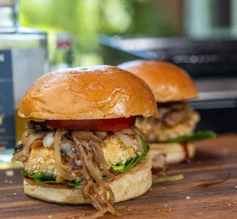 Knuspriger Reggie Burger mit paniertem Grillkäse, frischen Tomaten, Salat und BBQ-Soße auf geröstetem Bun