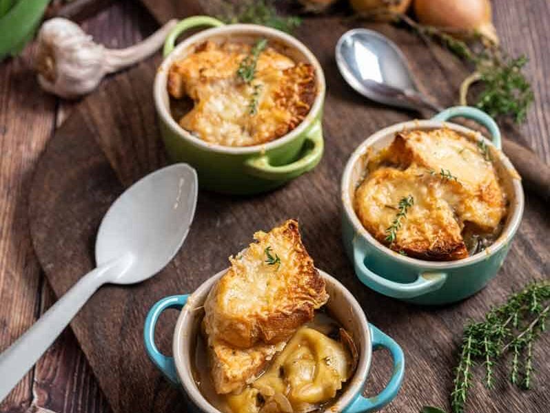 Zwiebelsuppe mit Tortellini, goldbraun gratiniertem Gruyère und Baguette in einer Suppentasse