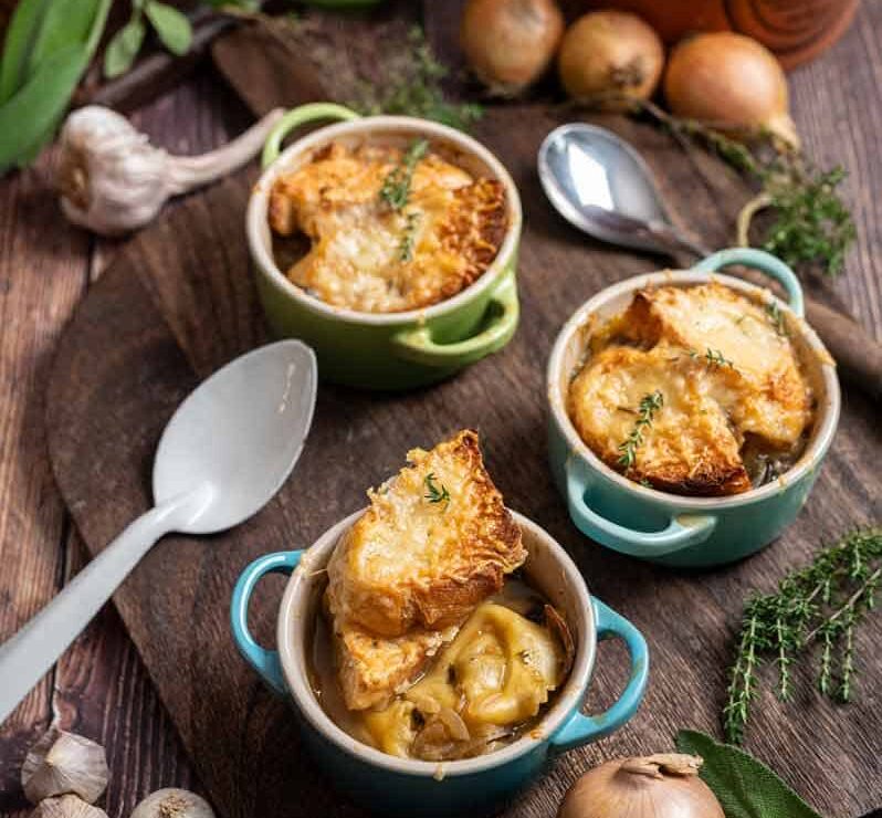 Zwiebelsuppe mit Tortellini, goldbraun gratiniertem Gruyère und Baguette in einer Suppentasse