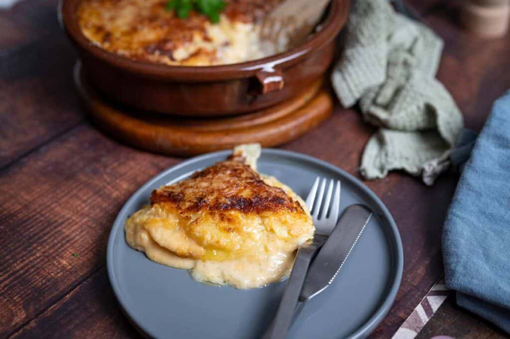 Vegetarisches Kartoffelgratin mit geschmolzenem Käse in einer weißen Auflaufform, bereit zum Servieren
